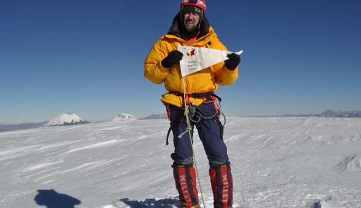 Juan García Arriaza, en la cima del Sajama posa orgulloso con el banderín de la SGE